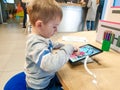 Portrait of little 3 years old toddler boy drawing on digital tablet at education center Royalty Free Stock Photo