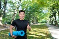 Portrait of yoga trainer, asian man looking at camera and smiling holding affirmative thumbs up, man in autumn park Royalty Free Stock Photo