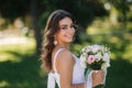 Portrait of yound girl with bouquet. Charming lady in sunny summer day. Stylish woman