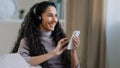 Portrait young active hispanic woman resting on couch at home arabian cheerful girl in apartment listening to music on