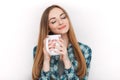 Portrait of a young adorable blonde woman in blue plaid shirt enjoying her warm cozy drink in big blank white mug. Royalty Free Stock Photo