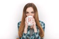 Portrait of a young adorable blonde woman in blue plaid shirt enjoying her warm cozy drink in big blank white mug. Royalty Free Stock Photo