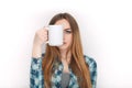 Portrait of a young adorable blonde woman in blue plaid shirt enjoying her warm cozy drink in big blank white mug. Royalty Free Stock Photo