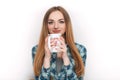 Portrait of a young adorable blonde woman in blue plaid shirt enjoying her warm cozy drink in big blank white mug. Royalty Free Stock Photo