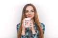 Portrait of a young adorable blonde woman in blue plaid shirt enjoying her warm cozy drink in big blank white mug. Royalty Free Stock Photo