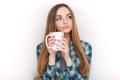 Portrait of a young adorable blonde woman in blue plaid shirt enjoying her warm cozy drink in big blank white mug. Royalty Free Stock Photo