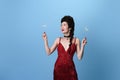 Portrait of young adorable gorgeous woman in dark red, wine color evening dress celebrating holiday isolated on blue