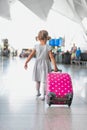 Portrait of young adorable little girl running in airport with her pink suitcase