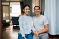 Portrait of young adult Asian couple embracing together with home interior in background. 30s happy mature husband and Royalty Free Stock Photo