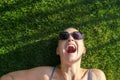 Portrait young adult bald shaved beautiful caucasian woman enjoy having fun lying on green grass lawn and smiling Royalty Free Stock Photo
