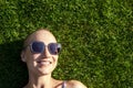 Portrait young adult bald shaved beautiful caucasian woman enjoy having fun lying on green grass lawn and smiling Royalty Free Stock Photo