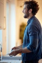 Portrait of young adult beardy male smiling while washing dishes