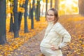 Portrait of young adult beautiful caucasian pregnant girl enjoy walking at scenic autumn city park. Happy woman smiling Royalty Free Stock Photo