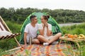 Portrait of young adult Caucasian man and a woman sitting near the tent at the lake or river, looking at each other, enjoying time Royalty Free Stock Photo