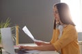 Portrait of young adult dark haired woman manager sitting at her workplace and working with documents, combines information with