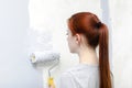 Portrait of young adult girl with red hair,woman painting walls with a gray brush roller,living,bedroom,moving to new apartment. Royalty Free Stock Photo