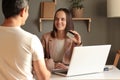 Portrait of young adult happy Caucasian banking advisor sitting in front of laptop and helping a male client posing backwards with Royalty Free Stock Photo