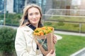 Portrait young adult smiling classy woman model hand holding authentic fresh orange spray roses flower bouquet wrapped Royalty Free Stock Photo