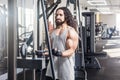 Portrait of young adult sport athlete man with long curly hair training at gym alone, standing and lifting weights in the gym, Royalty Free Stock Photo