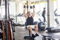 Portrait of young adult sport man training at gym alone. athlete working out in a gym, sitting and holding two dumbbell with Royalty Free Stock Photo
