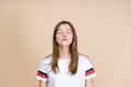 Portrait of young adult woman waiting kiss while standing isolated on pastel beige background