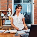 Portrait of young advertising agent holding papers standing at her workplace in agency with creative interior