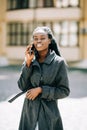 Portrait of young african american girl talking by mobile phone, smiling. Sunny day. Outdoor photo Royalty Free Stock Photo