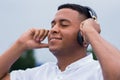 Portrait of a young African American man with eyes closed. Holding headphones and listening to music. Royalty Free Stock Photo