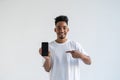 Portrait of happy young african american man holding mobile phone and pointing to screen Royalty Free Stock Photo