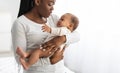 Black mother holding crying baby with colic on hands