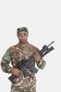 Portrait of young African American US Marine Corps soldier with M4 assault rifle over gray background