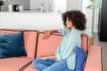 Portrait of young african-american woman with beautiful smile and looking aside dreamly sitting on the sofa Royalty Free Stock Photo
