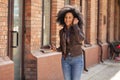Portrait of young African American woman cute smiling. Brunette with curly hair in leather jacket posing on street Royalty Free Stock Photo