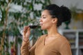 Portrait of a young African American woman drinking red wine from glass goblet. Cute mixed race female is enjoying taste