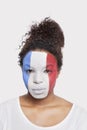 Portrait of young African American woman with French flag painted on face against white background Royalty Free Stock Photo