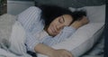 Portrait of young African American woman lying in bed and falling alseep in comfortable bedroom