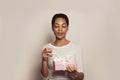 Portrait of young african american woman opening present box with white ribbon. Happy female model with pink gift Royalty Free Stock Photo