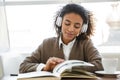 Portrait of young african american woman reading book on sofa in cafe Royalty Free Stock Photo