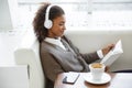 Portrait of young african american woman reading book on sofa in cafe Royalty Free Stock Photo