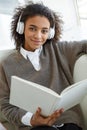 Portrait of young african american woman reading book on sofa in cafe Royalty Free Stock Photo