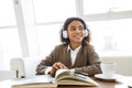 Portrait of young african american woman reading book on sofa in cafe Royalty Free Stock Photo