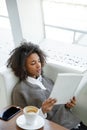 Portrait of young african american woman reading book on sofa in cafe Royalty Free Stock Photo