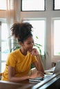 Portrait of young African American woman sitting in cozy home working remotely, surfing internet on laptop Royalty Free Stock Photo