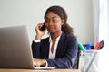 Young african businesswoman working on laptop and making phone call Royalty Free Stock Photo