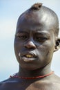 Portrait of Young African Man with Painted Body in the local Mursi tribe village