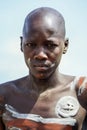 Portrait of Young African Man with Painted Body in the local Mursi tribe village