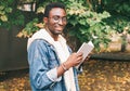 Portrait young african man student with a book looking away wearing an eyeglasses in autumn city park Royalty Free Stock Photo