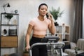 Portrait of young african sportive woman in sportswear talking on smartphone while training at home Royalty Free Stock Photo
