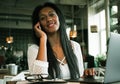 Portrait of young african woman relaxing in cafe with laptop and making phone call Royalty Free Stock Photo