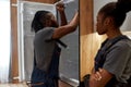 Gender inequality. Female repair service worker standing by male technician repairing fridge